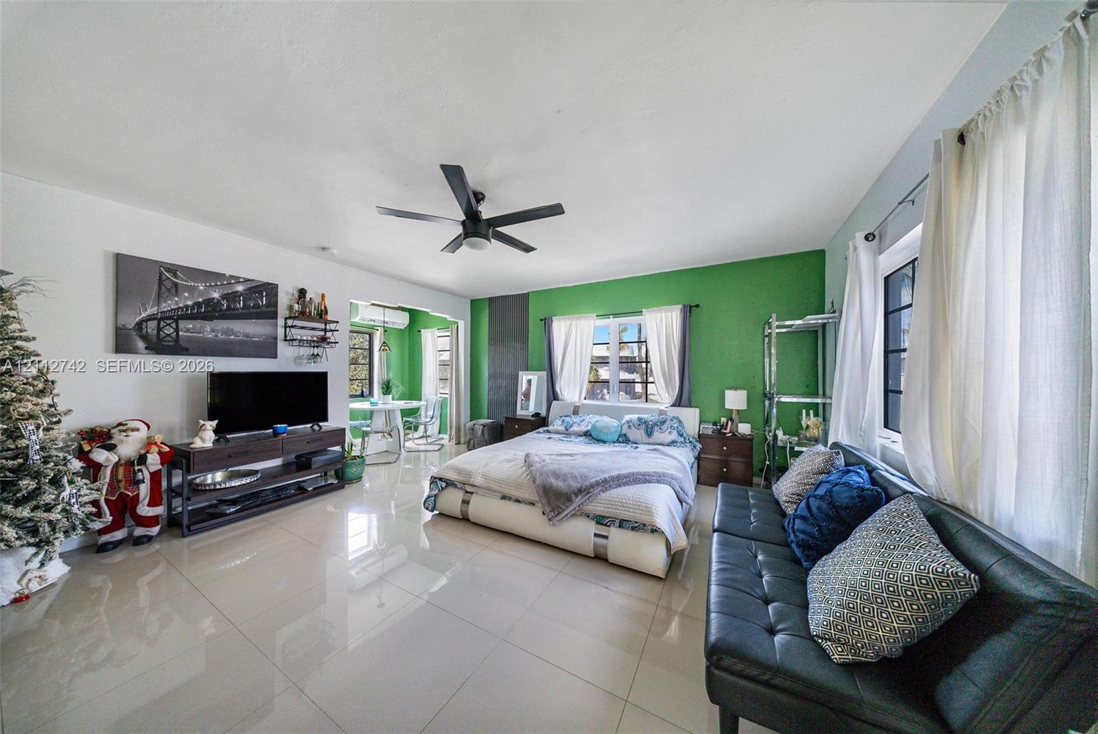 Spacious room featuring polished tile flooring, ceiling fan, and large windows with integrated hardware