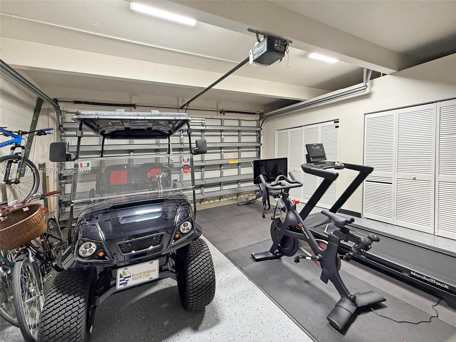 Multi-car garage featuring epoxy-coated flooring, built-in wall shelving, and dual sets of louvered-door closets