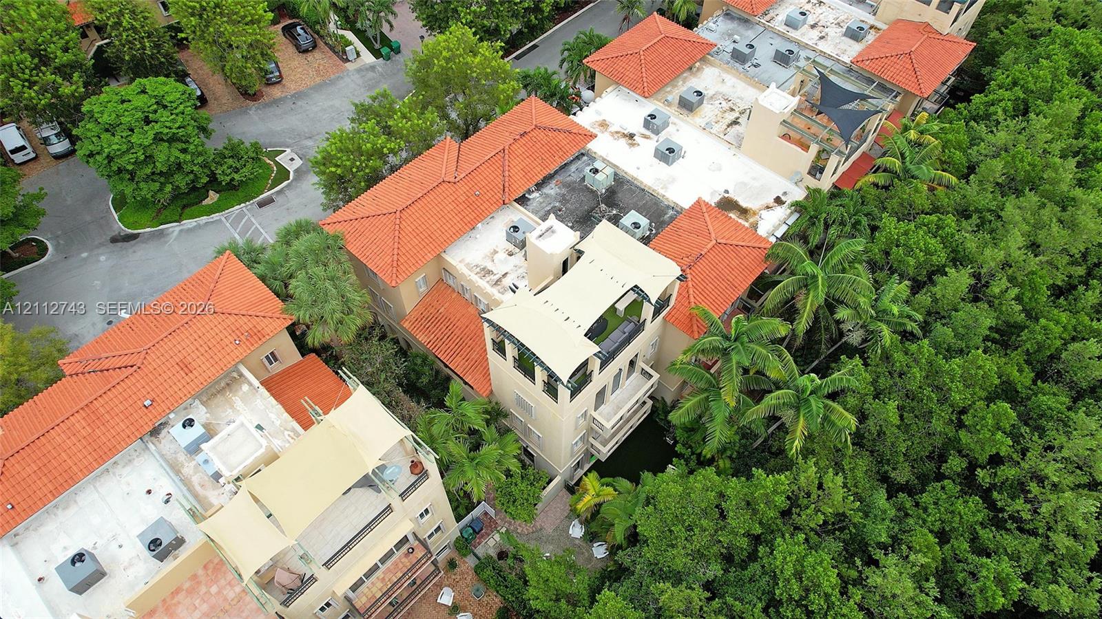 Aerial perspective featuring multi-story structures with terracotta tile roofing, stucco exteriors, upper-level balconies, and rooftop terraces
