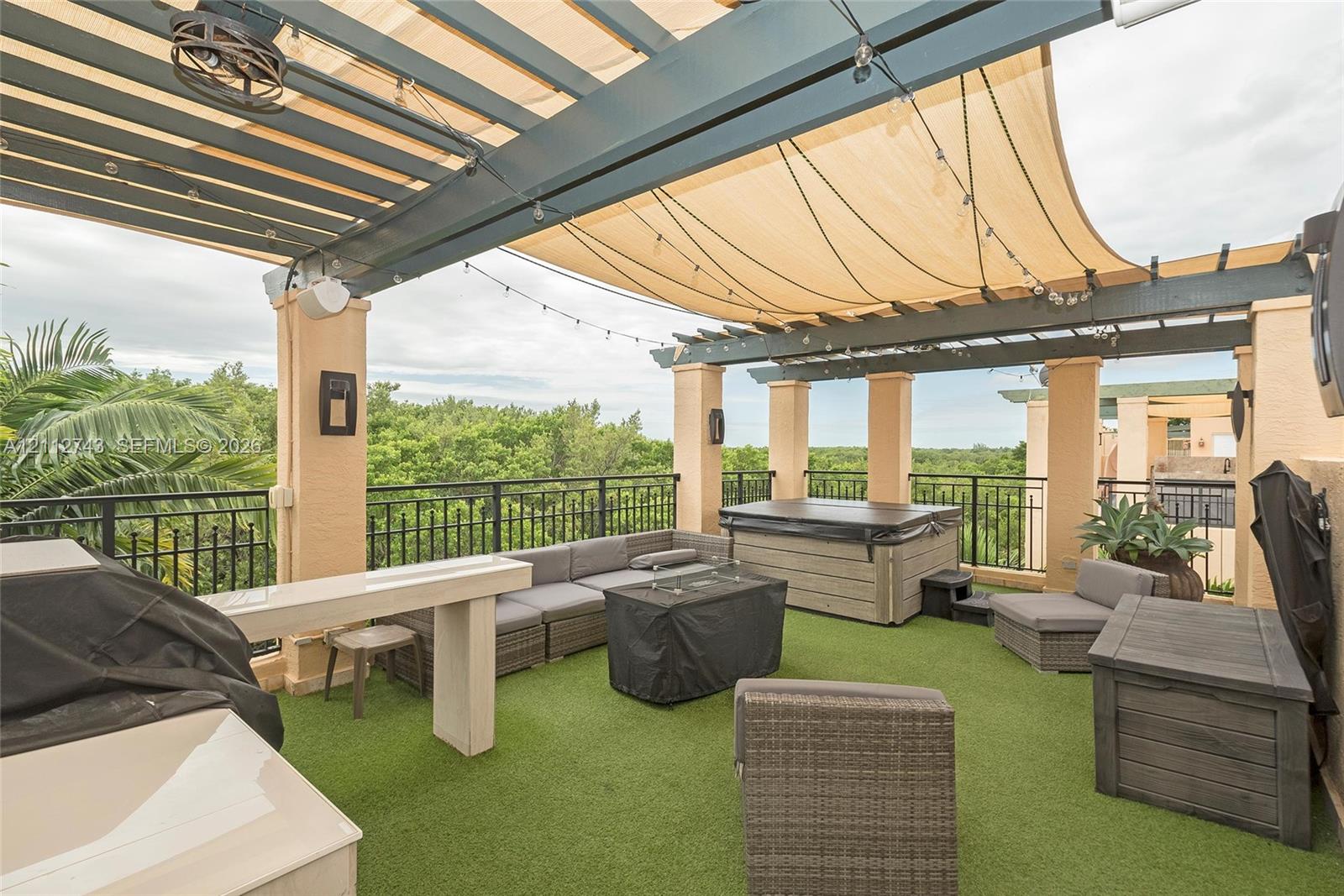 Rooftop terrace featuring a covered pergola, integrated overhead lighting, metal railings, and a built-in outdoor kitchen structure