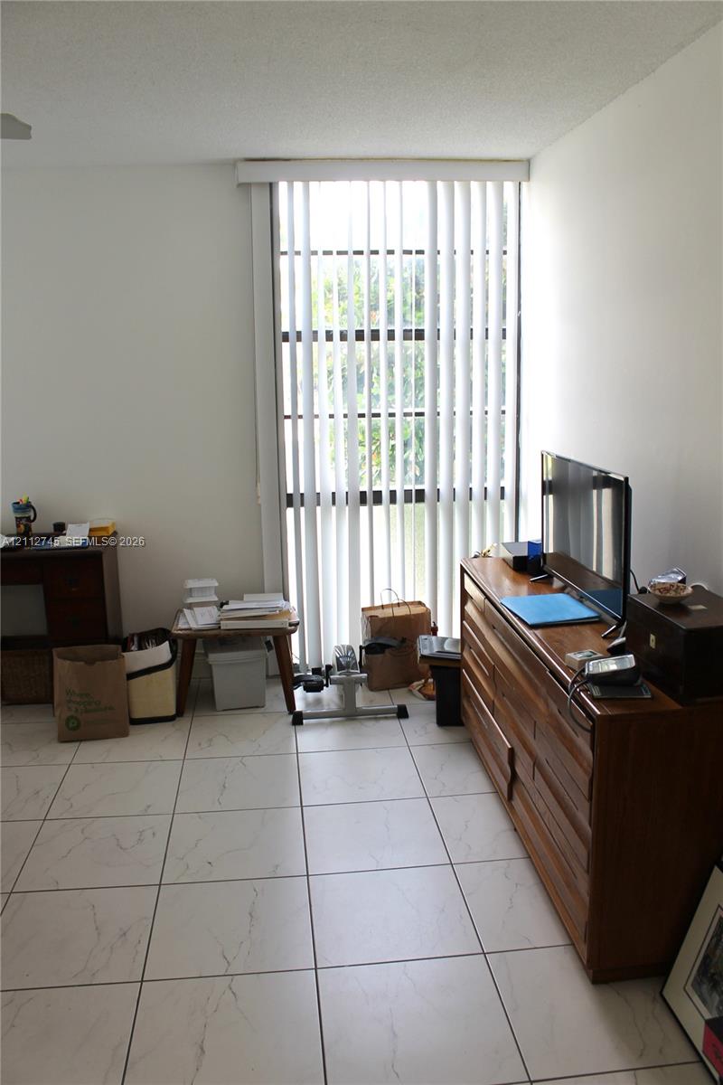 Floor-to-ceiling window with vertical blinds and white stone-finish tile flooring