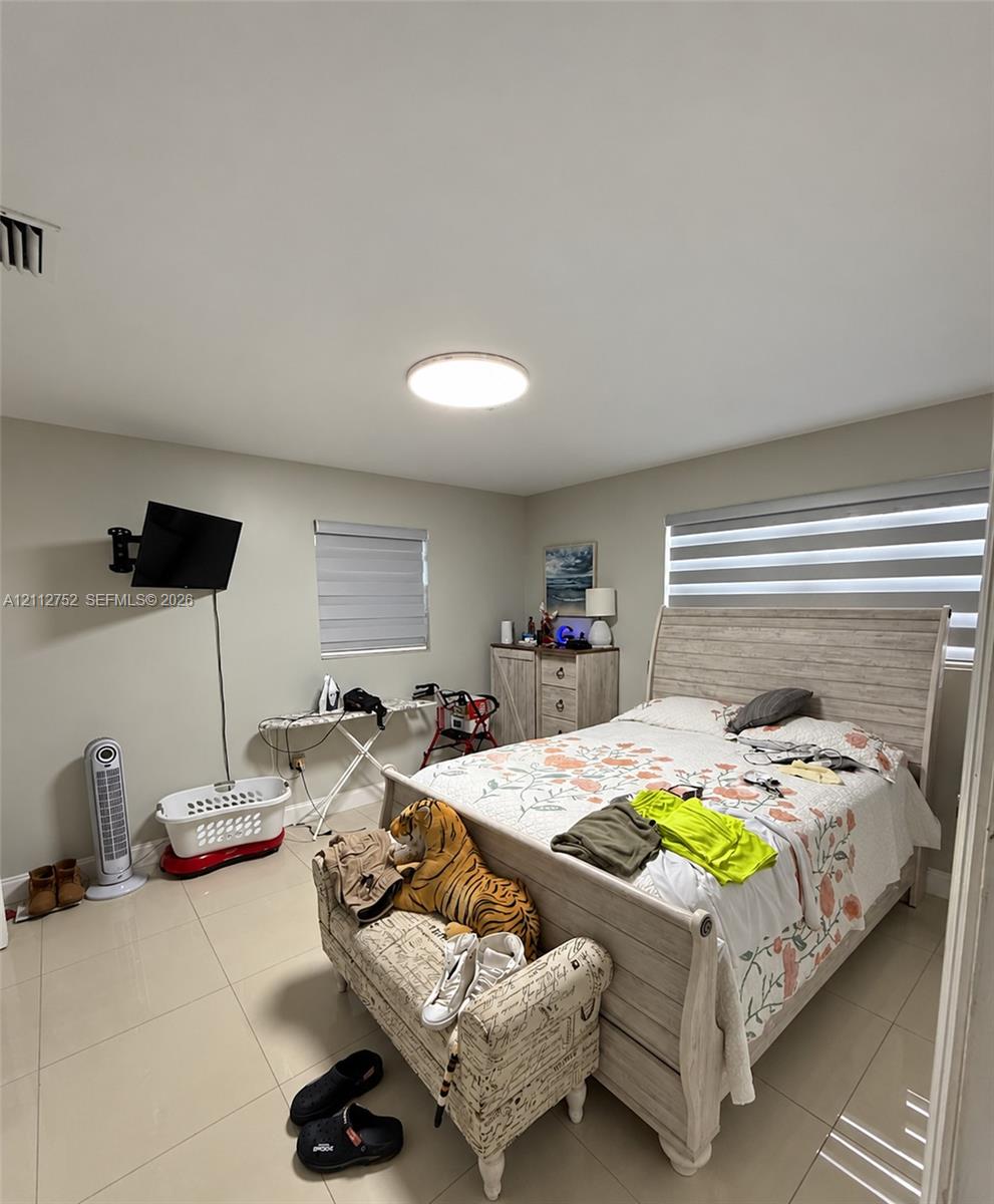 Neutral wall tones, ceramic tile flooring, and dual-layered window shades