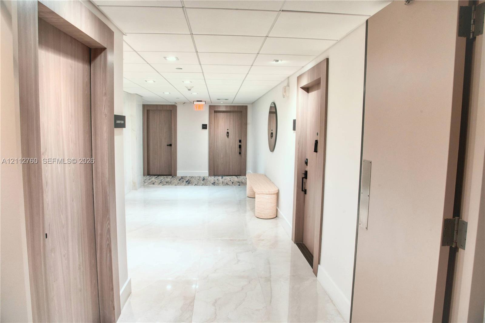 Interior hallway featuring polished stone-finish flooring, recessed ceiling lighting, and wood-finish door frames