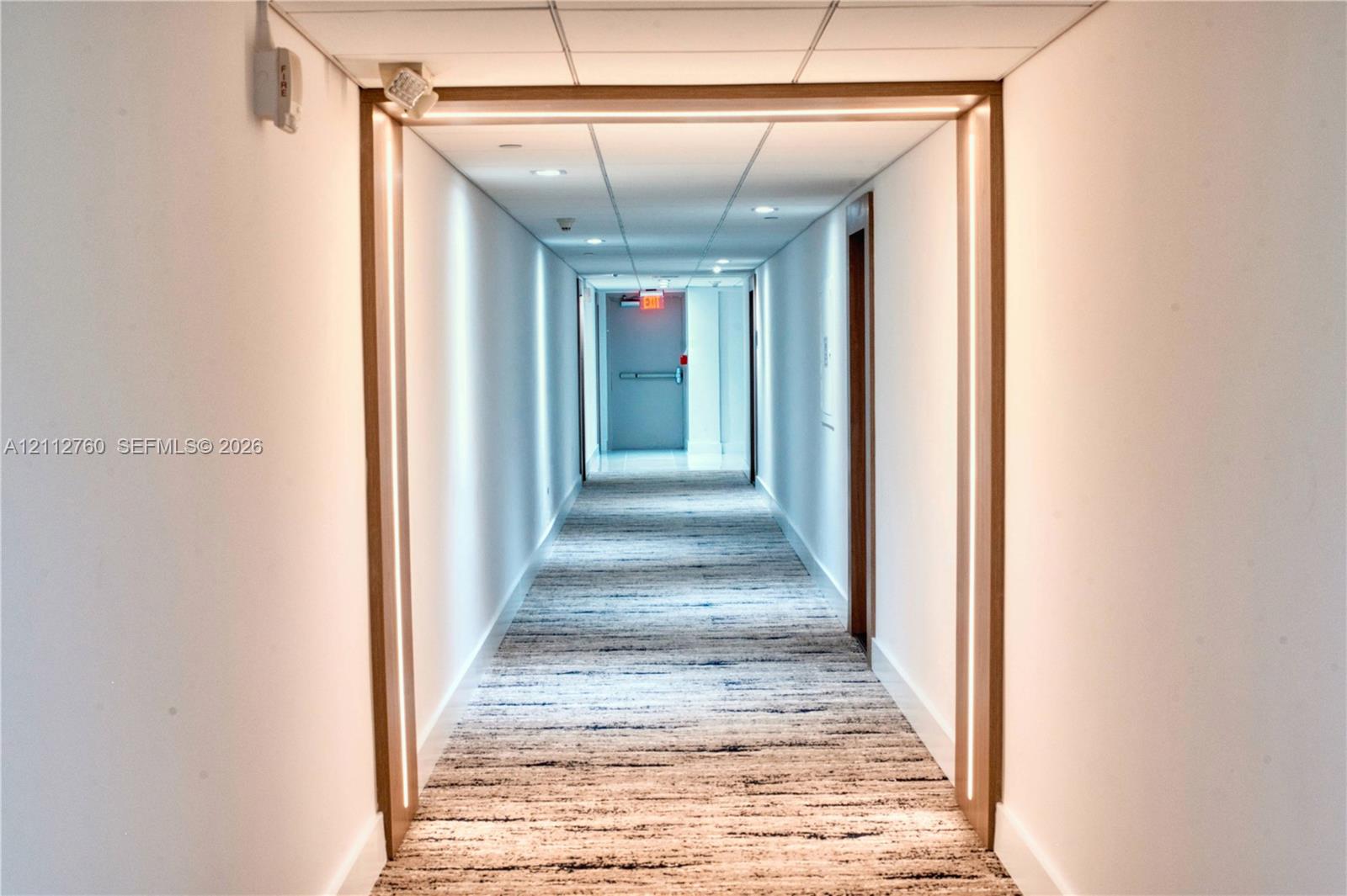 Hallway featuring integrated linear LED lighting, wood-trim portal framing, recessed ceiling lighting, and textured carpeting