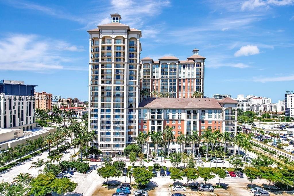 High-rise residential exterior featuring multi-story masonry construction, arched architectural detailing, private balconies, and surrounding mature landscaping
