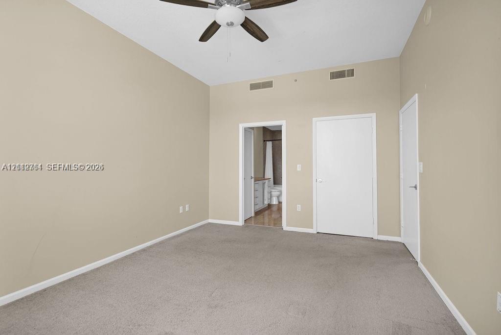 Room featuring vaulted ceilings, neutral wall tones, wall-to-wall carpeting, and a ceiling fan with integrated lighting