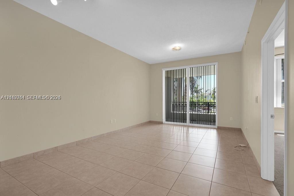 Interior space featuring neutral-toned wall paint, ceramic tile flooring, and a sliding glass door with vertical blinds providing exterior access