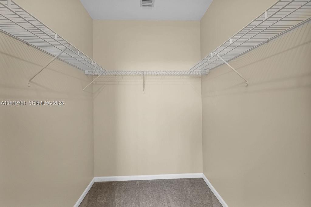 Storage closet featuring neutral wall paint, gray carpeting, and white wire shelving