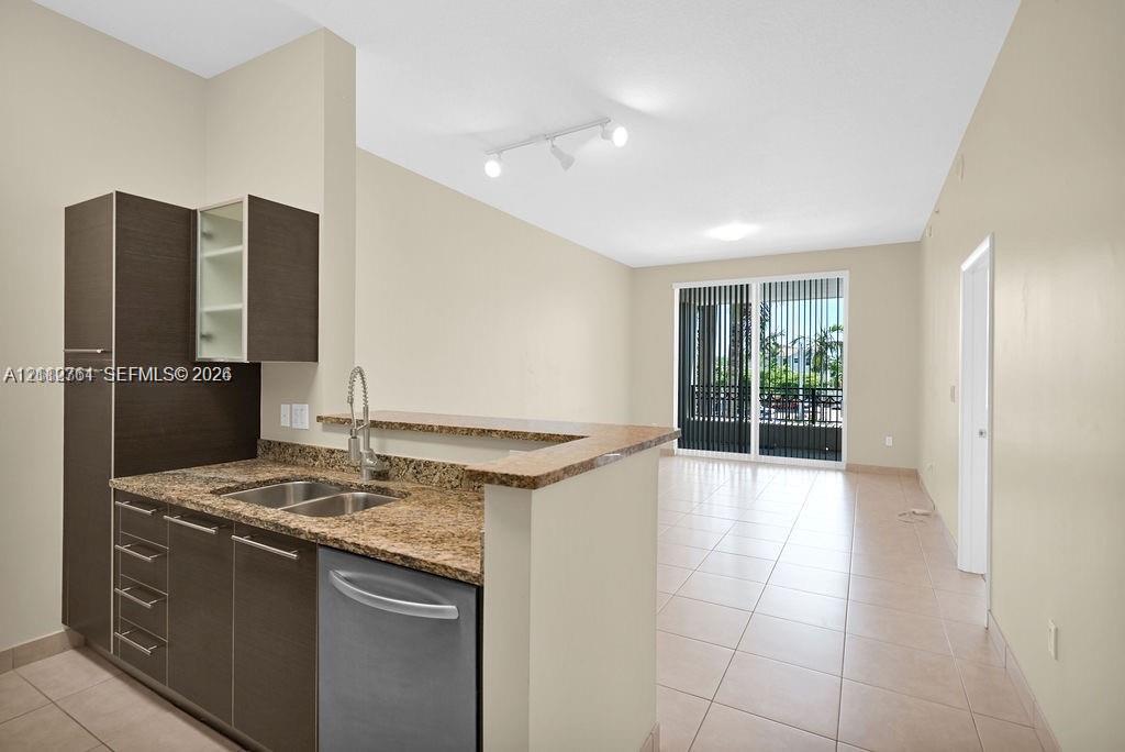 Kitchen featuring dark cabinetry, stone-finish countertops, stainless steel dual-basin sink, and ceramic tile flooring throughout Kitchen featuring dark cabinetry, stone-finish countertops, stainless steel dual-basin sink, and ceramic tile flooring throughout