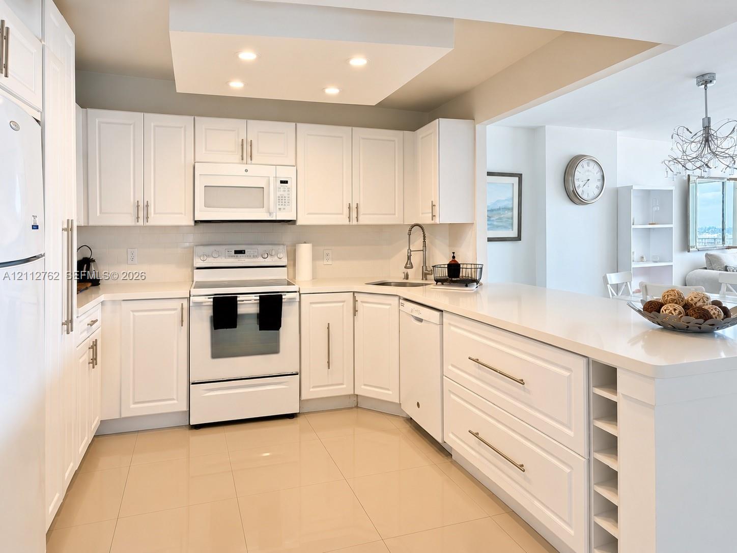 Kitchen featuring white shaker-style cabinetry, solid-surface countertops, recessed ceiling lighting, tile flooring, and integrated wine storage