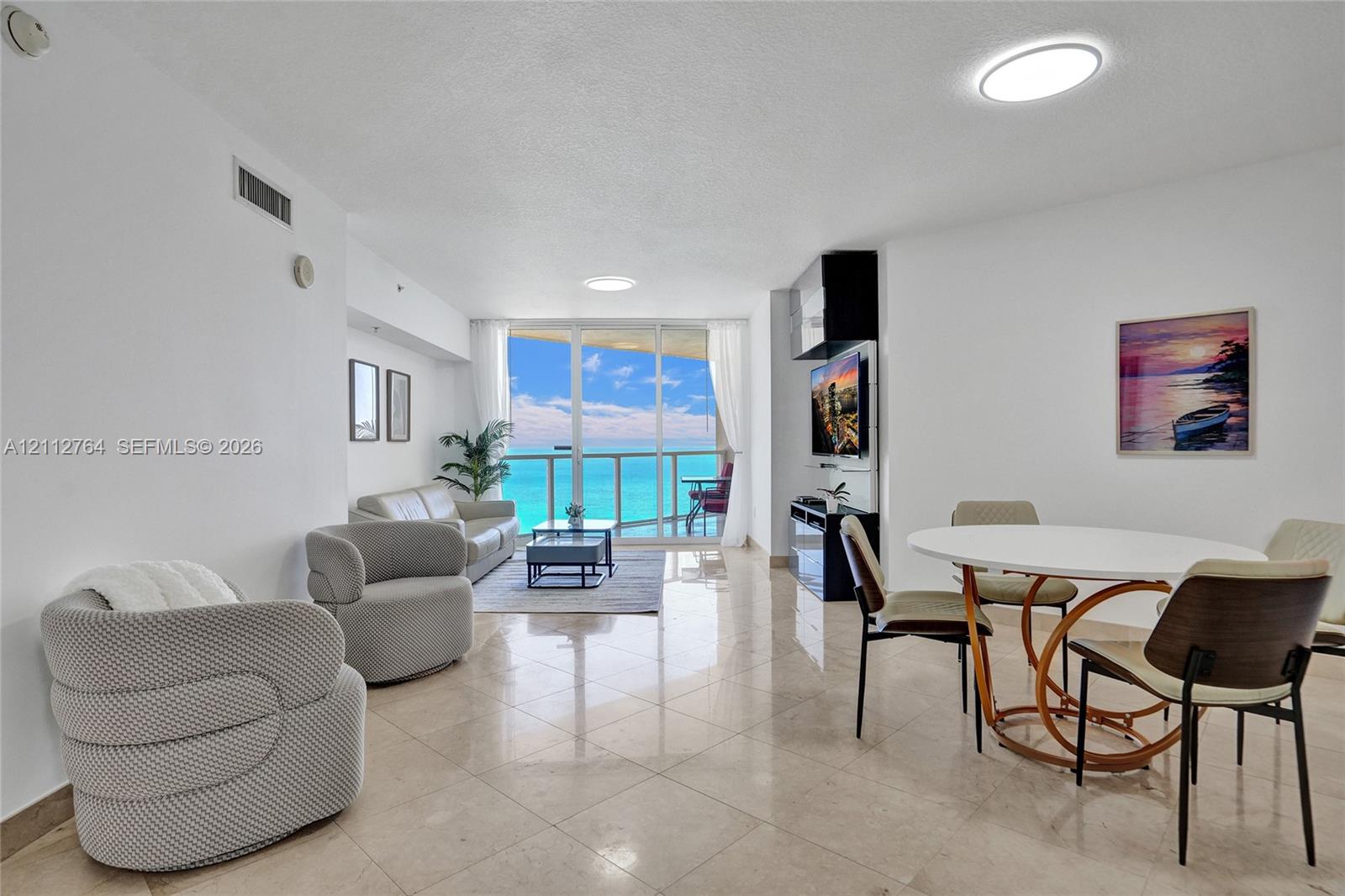 Open-concept living space featuring polished stone flooring, floor-to-ceiling glass sliding doors, and a built-in media console