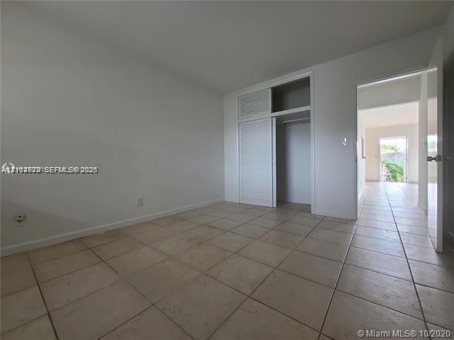 Neutral-toned ceramic tile flooring and built-in closet with louvered doors