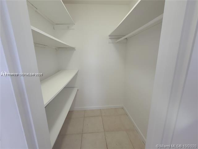 Walk-in storage space featuring ceramic tile flooring and tiered built-in shelving