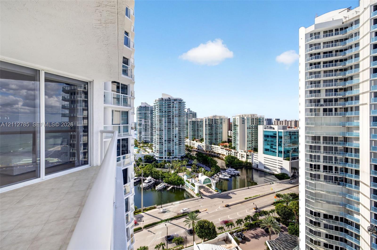 Private balcony with tile flooring and glass railings featuring panoramic urban and waterfront exposures