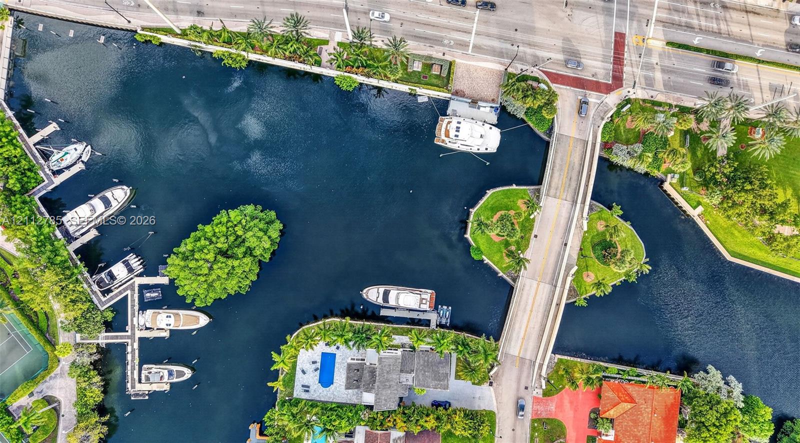 Waterfront property featuring a private boat dock, deep-water canal access, a paved deck, and a tennis court