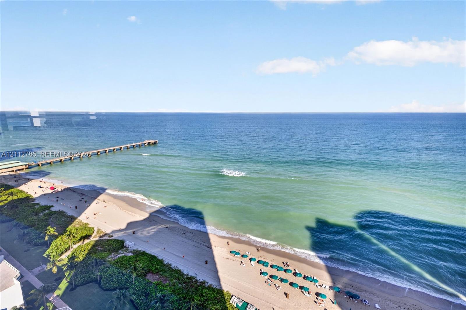 Elevated oceanfront perspective featuring expansive water horizons, direct sandy coastline access, and a structural pier