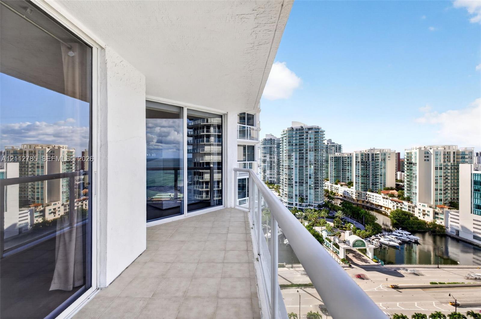 Covered balcony featuring tile flooring, glass panel railings, and floor-to-ceiling sliding glass doors