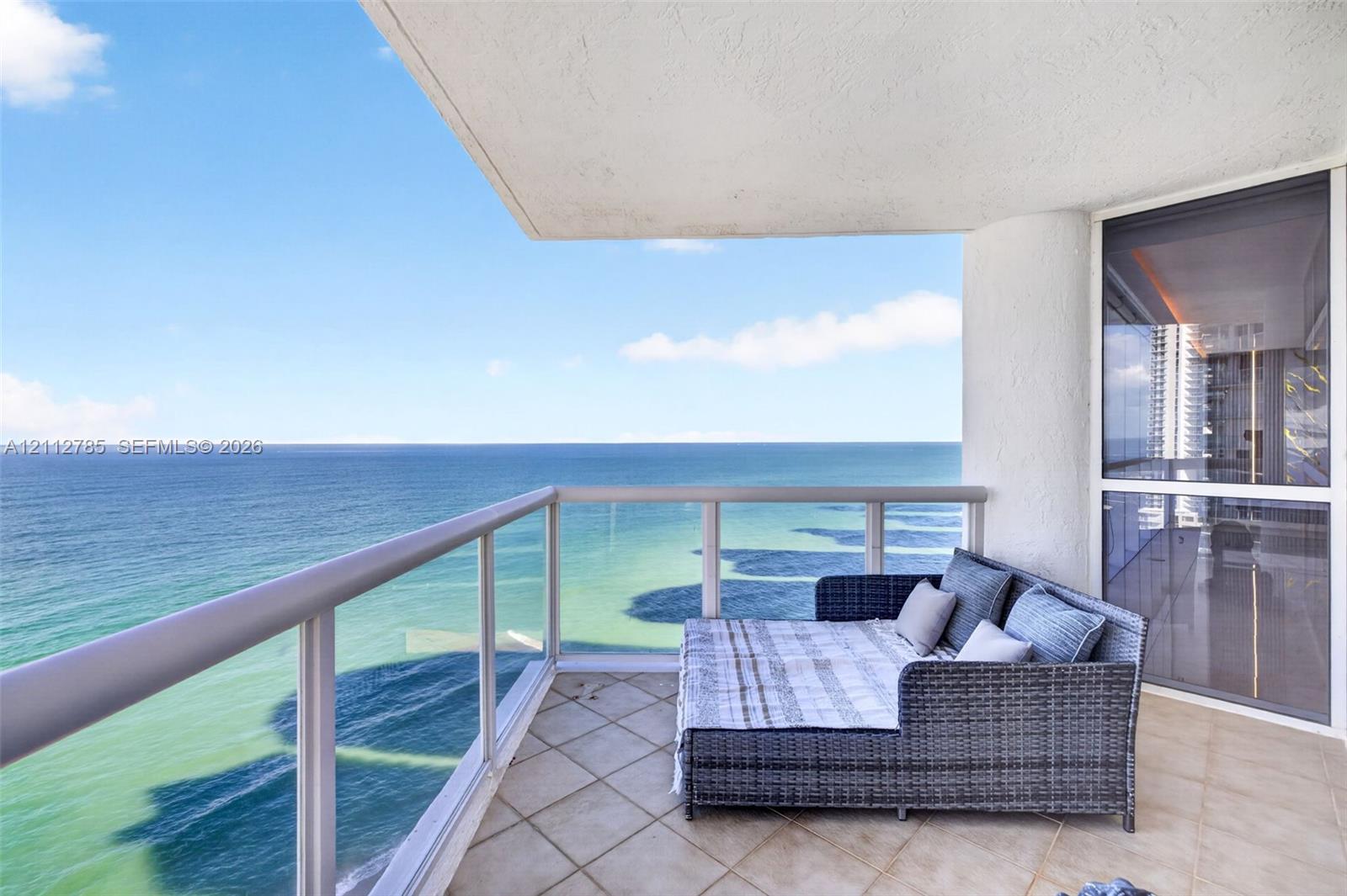 Covered balcony featuring tile flooring, glass and metal railings, and direct ocean water frontage Covered balcony featuring tile flooring, glass and metal railings, and direct ocean water frontage