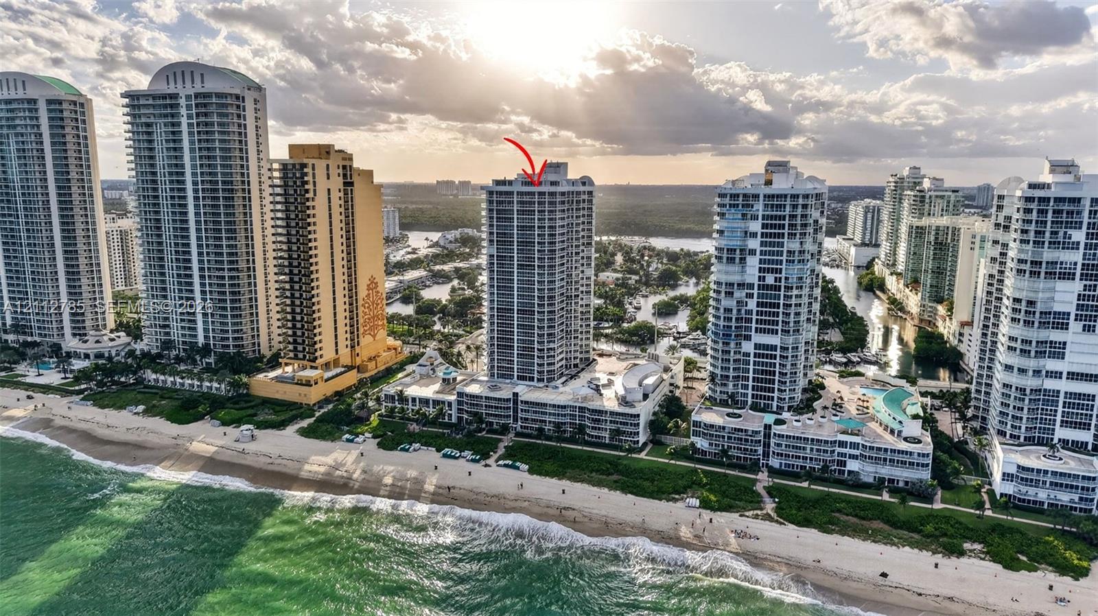 High-rise residential building featuring floor-to-ceiling glass windows, multiple balconies, and a prime coastal location directly bordering the Atlantic Ocean