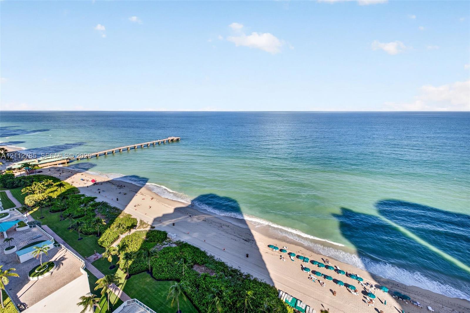 Panoramic oceanfront exposure featuring an expansive coastal horizon, sandy beach shoreline, and a prominent pier structure