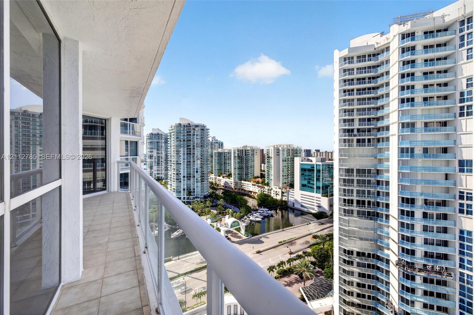 Covered balcony featuring tile flooring and a glass-paneled railing