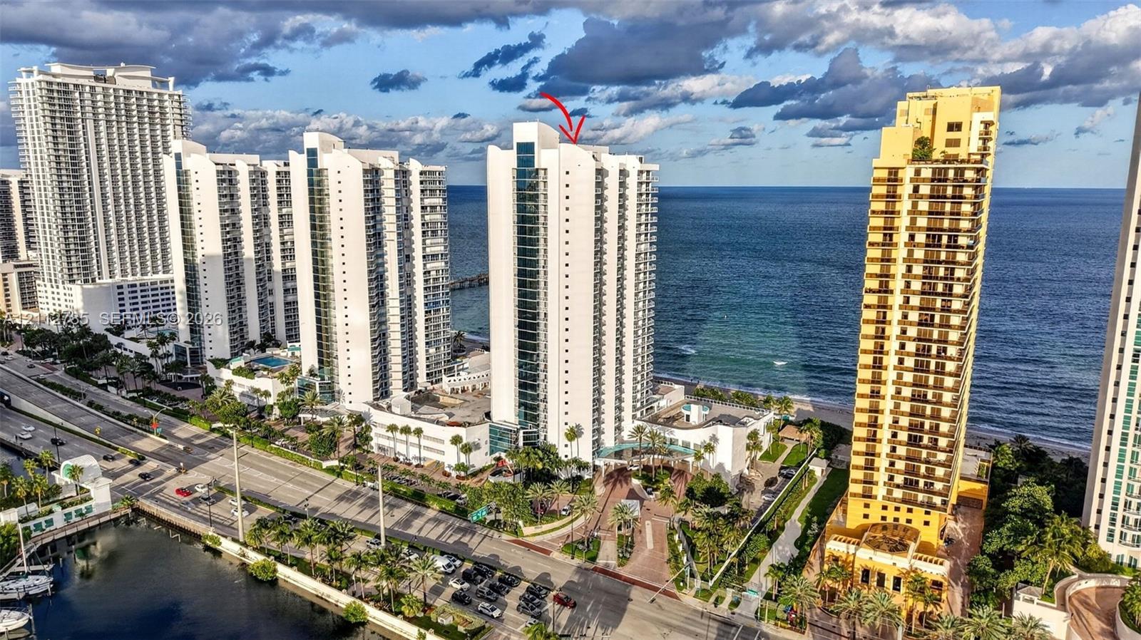 High-rise residential tower featuring a glass and concrete facade, direct ocean frontage, and a prominent position within a coastal landscape