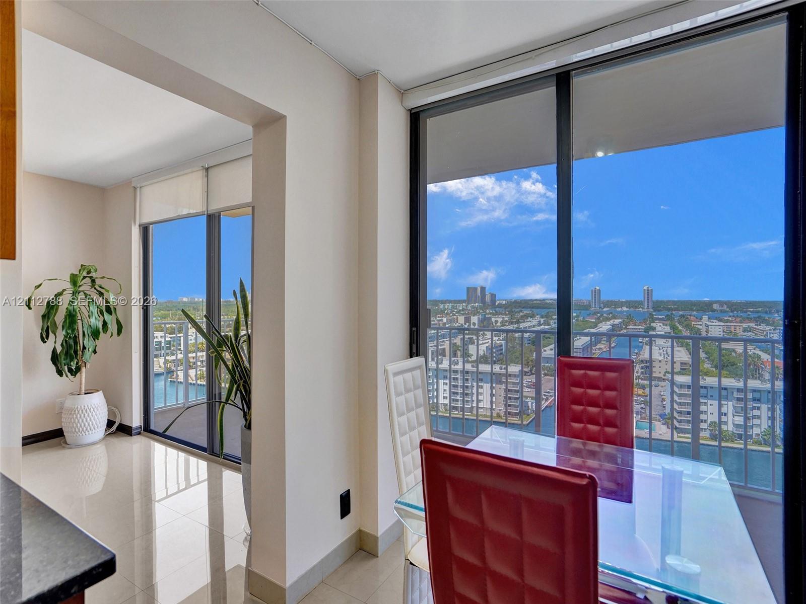 Floor-to-ceiling windows, polished tile flooring, black metal balcony railings, and expansive cityscape scenery