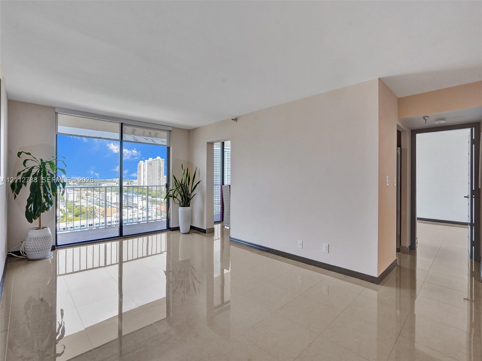 Open-concept interior featuring large-format tile flooring, expansive sliding glass doors, and a private balcony