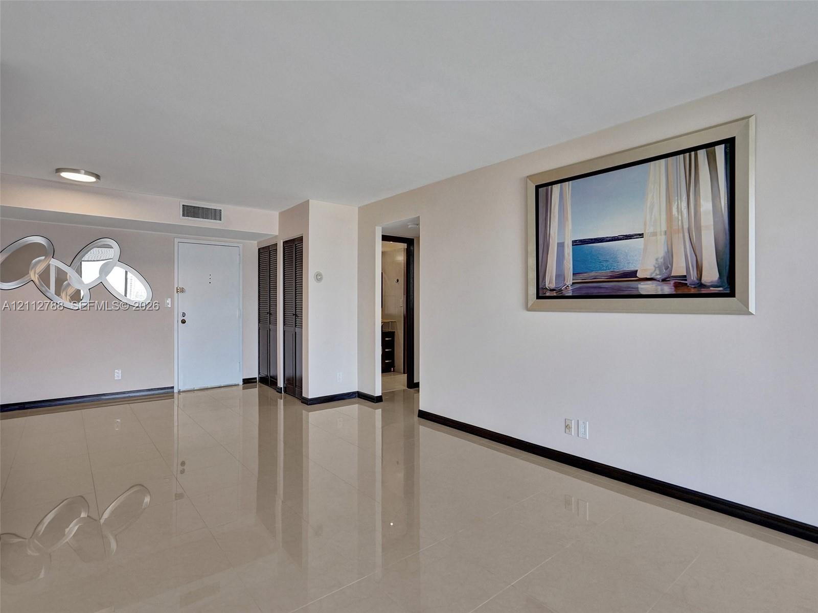 Spacious interior featuring large-format tile flooring, neutral wall tones, and recessed ceiling lighting