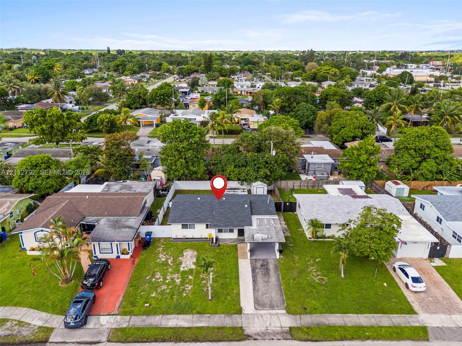 Single-story residence featuring a shingle roof, attached carport, concrete driveway, and a white privacy fence