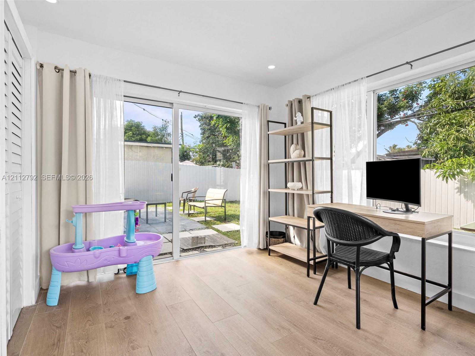 Wood-finish flooring, recessed lighting, and large sliding glass doors providing external access
