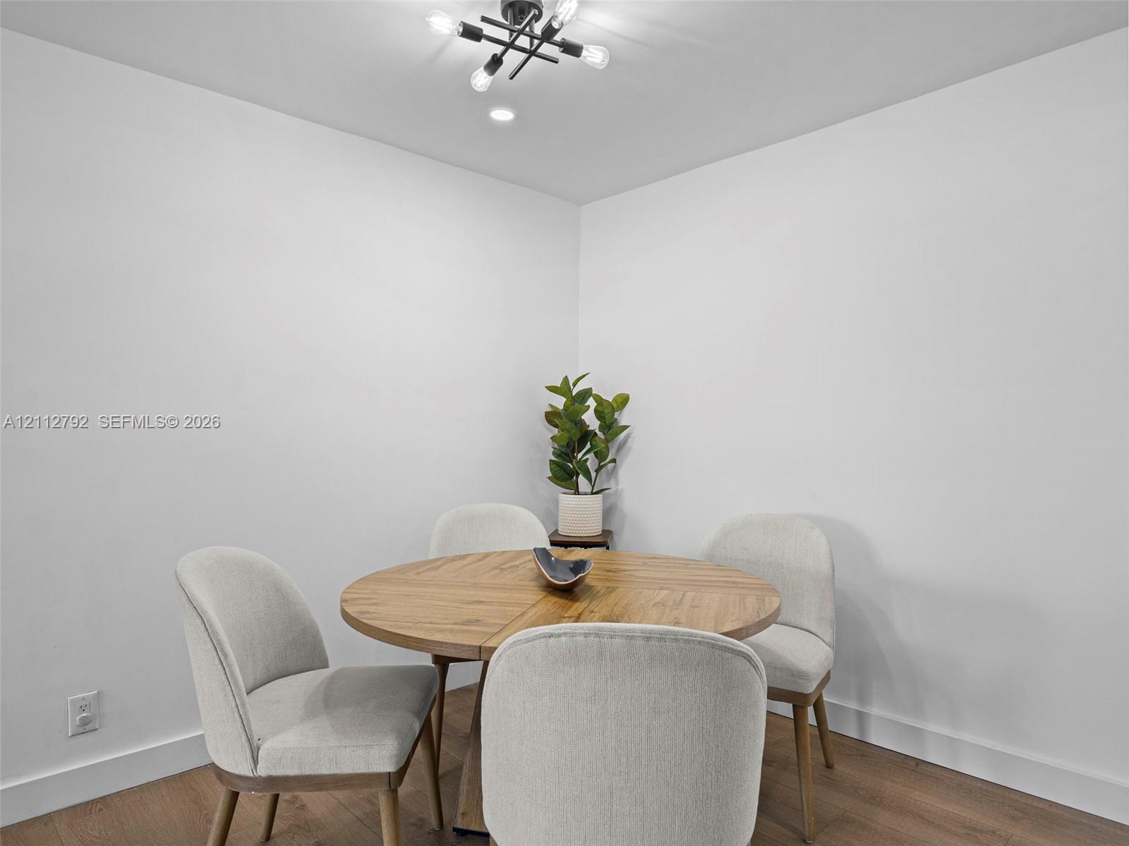Wood-finish flooring, neutral walls, and a modern multi-bulb overhead light fixture