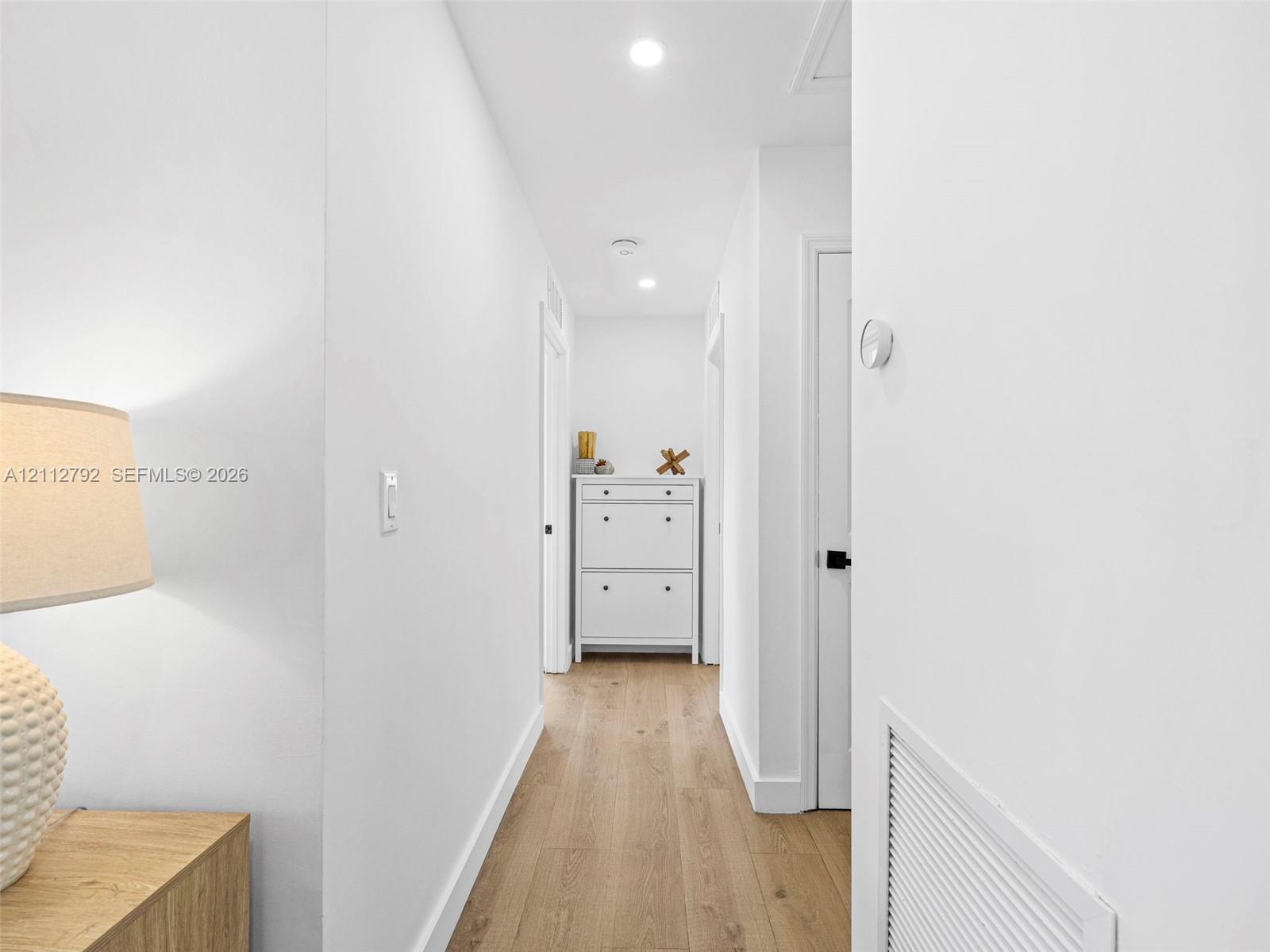 Hallway featuring wood-finish flooring, recessed lighting, and crisp white wall finishes