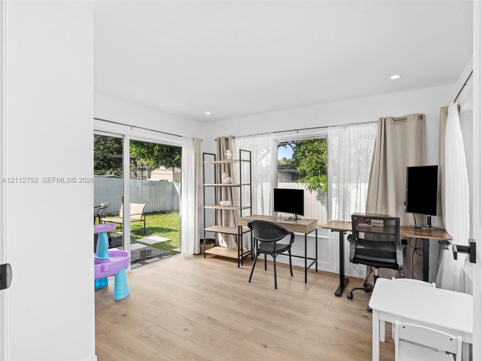 Interior space featuring wood-finish flooring, sliding glass door, and large window expanse with recessed lighting