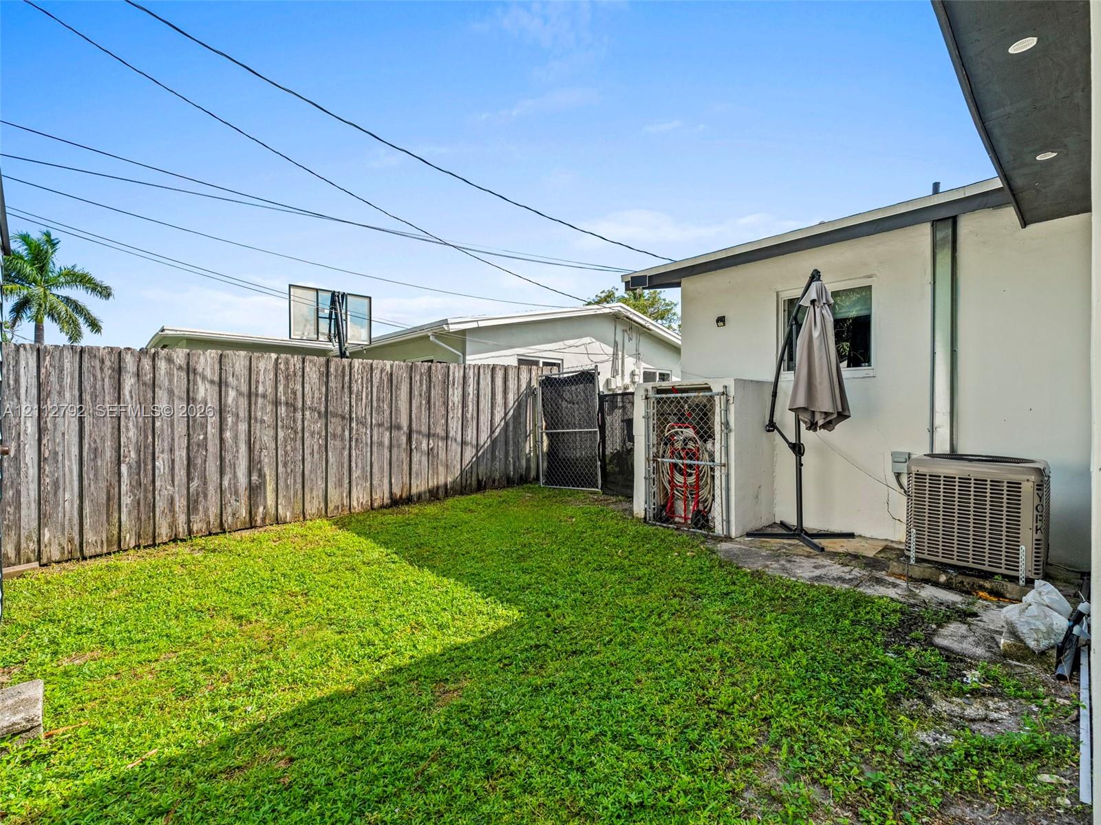 Fenced backyard featuring a grass lawn, metal enclosure, and recessed exterior lighting