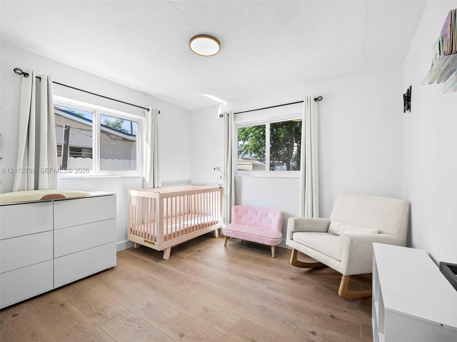 Neutral-toned room featuring wood-finish flooring, two sliding windows, and a flush-mount light fixture