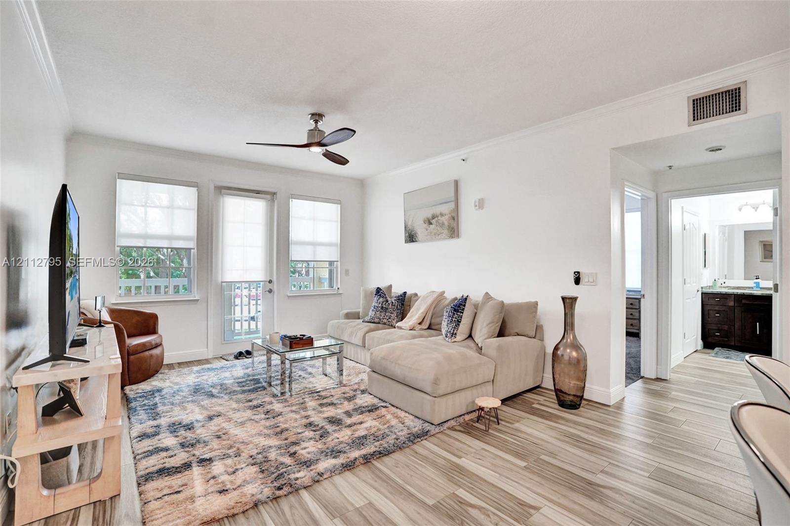 Living area featuring wood-finish flooring, ceiling fan, and access to an exterior balcony