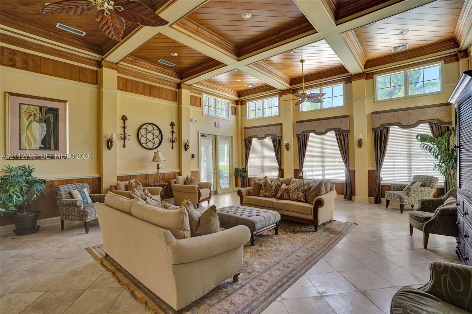 Coffered ceiling with wood paneling, tile flooring, and oversized windows