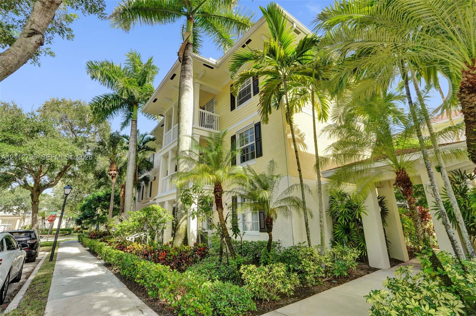 Multi-story exterior featuring lap siding, shutter-framed windows, multi-level balconies with railing, and integrated palm tree landscaping