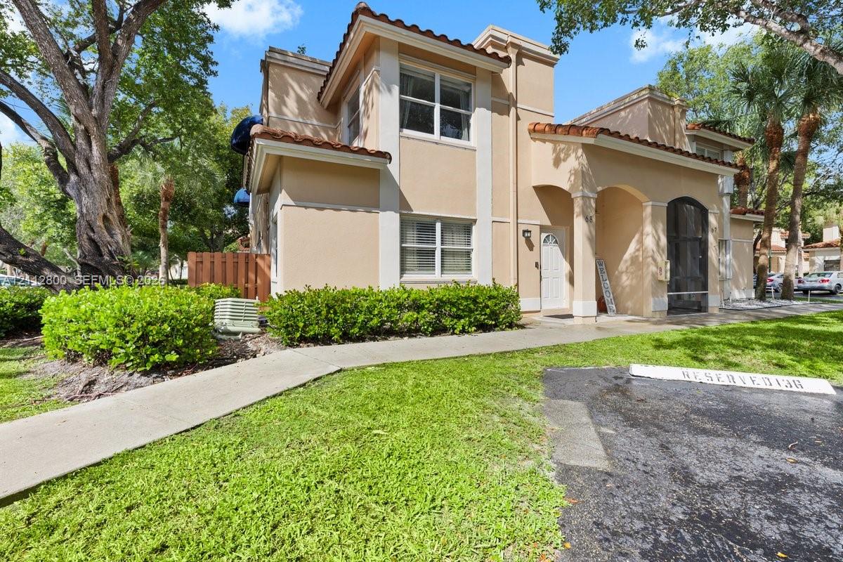 Stucco exterior featuring arched architectural detailing, a tiled roofline, and a covered entryway Stucco exterior featuring arched architectural detailing, a tiled roofline, and a covered entryway