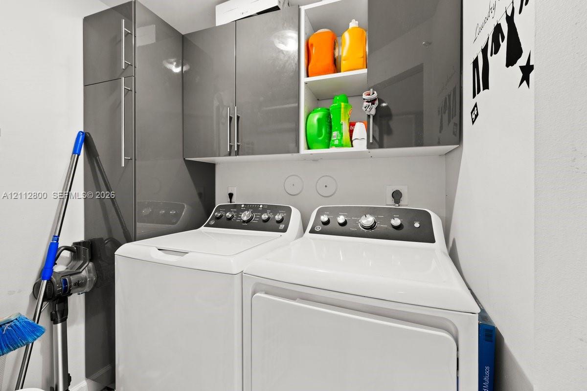 Laundry area featuring high-gloss charcoal grey cabinetry, integrated tall storage, and stainless steel hardware