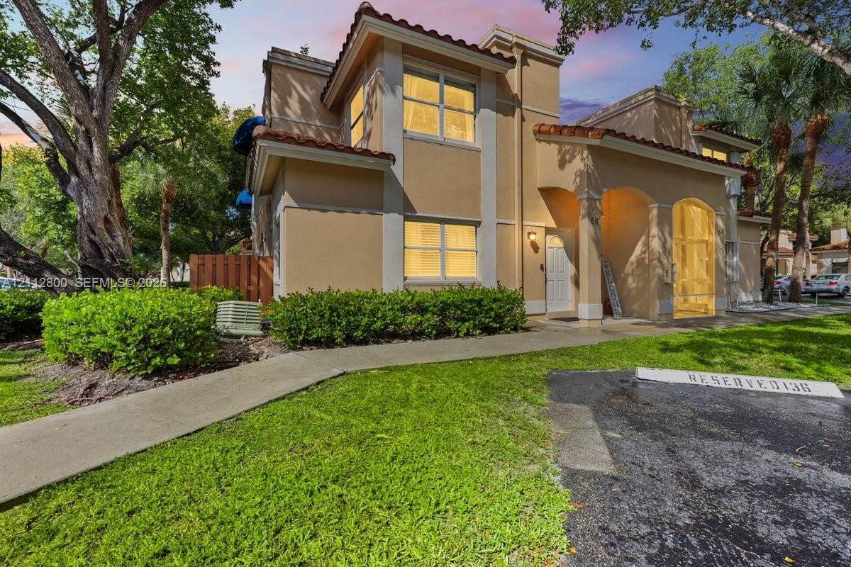 Stucco exterior featuring arched architectural detailing, a terracotta tile roof, and a paved walkway