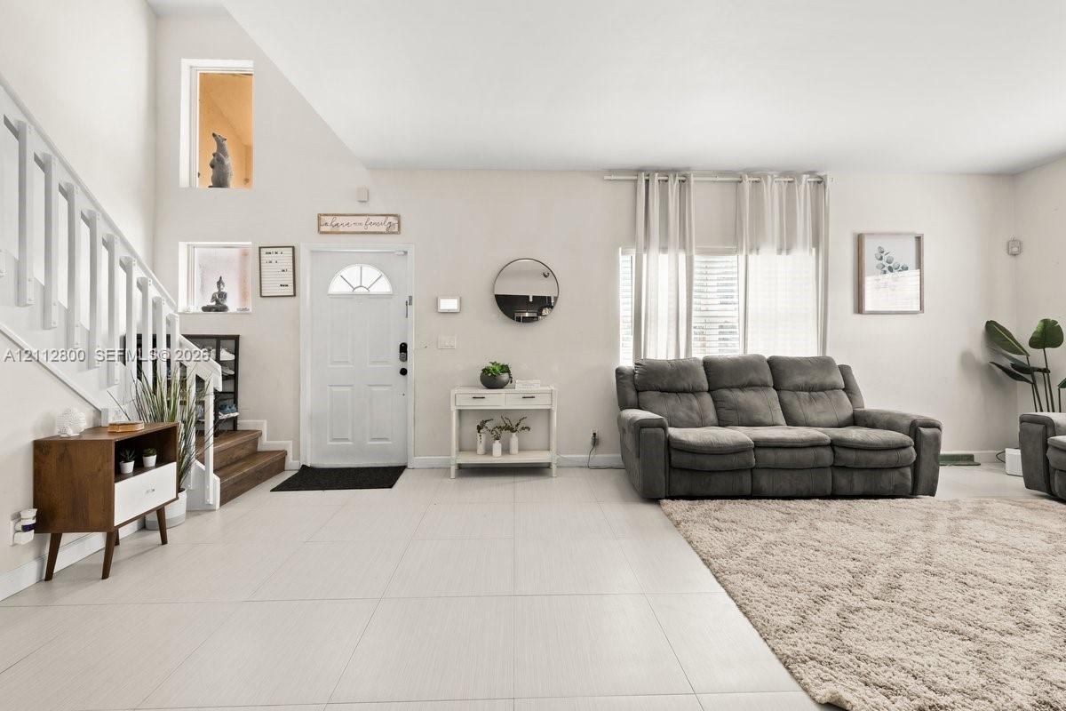 High-ceiling interior featuring tile flooring, a staircase with painted wood railings, multiple recessed wall niches, and a multi-paneled entry door
