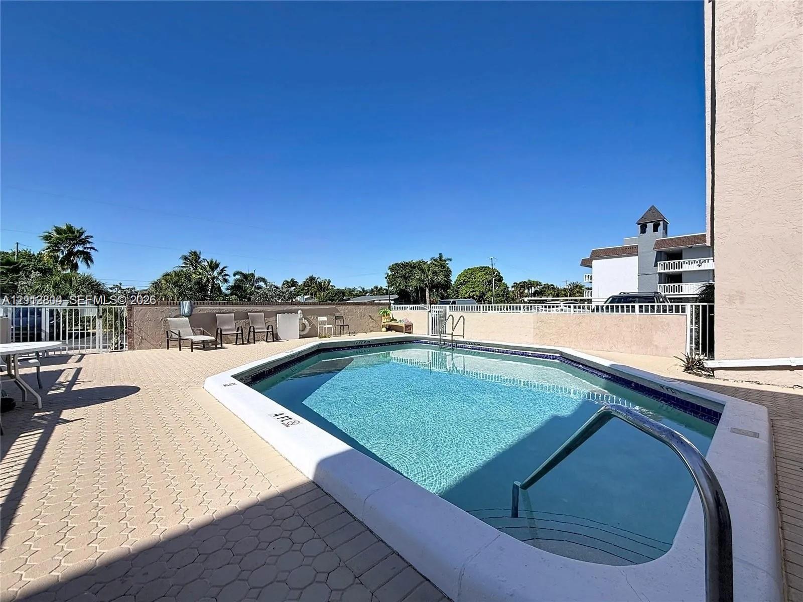 In-ground swimming pool with metal ladder and tiled pool deck perimeter