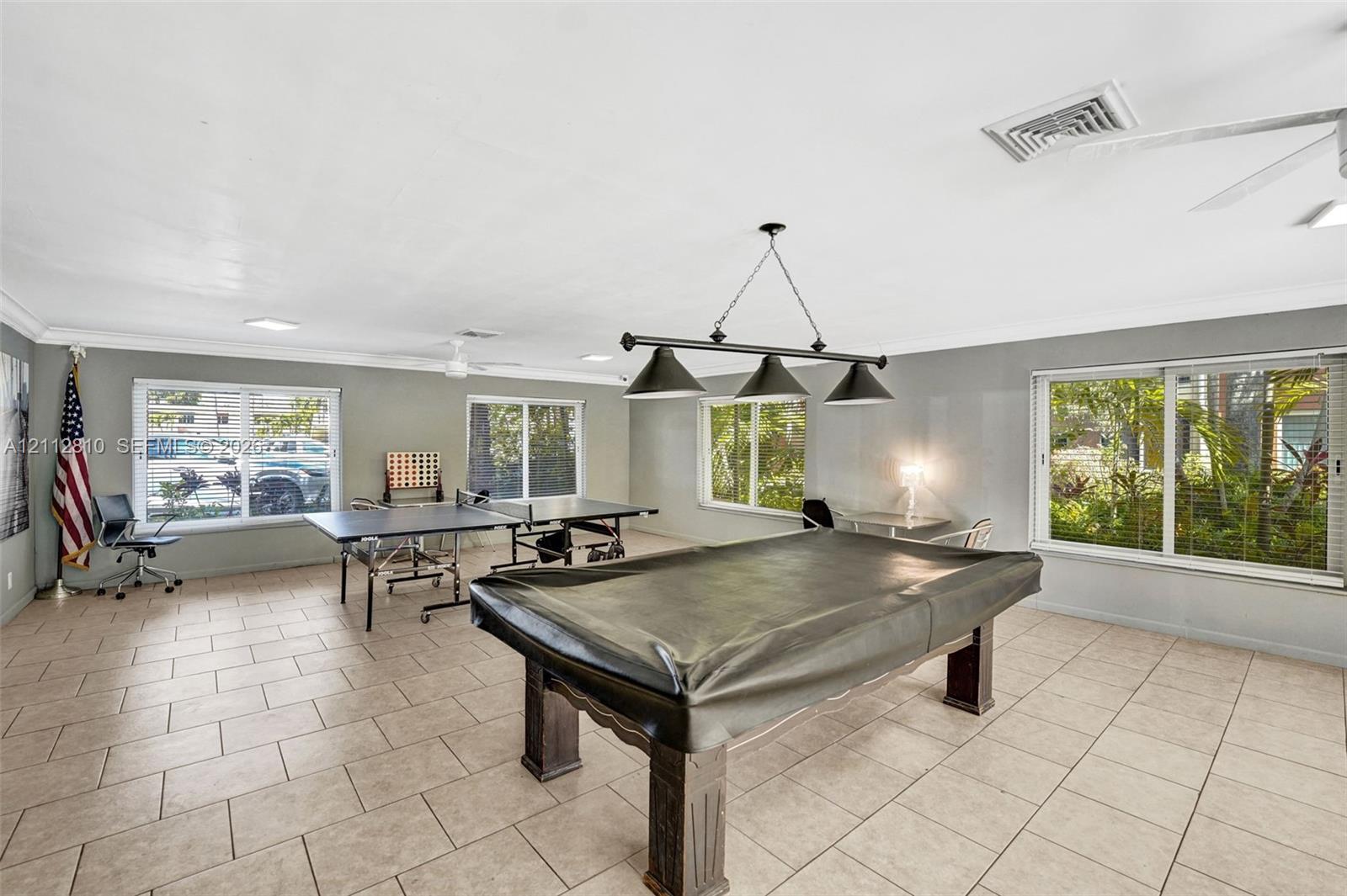 Spacious room featuring tile flooring, crown molding, a three-light pendant fixture, recessed lighting, and multiple large windows