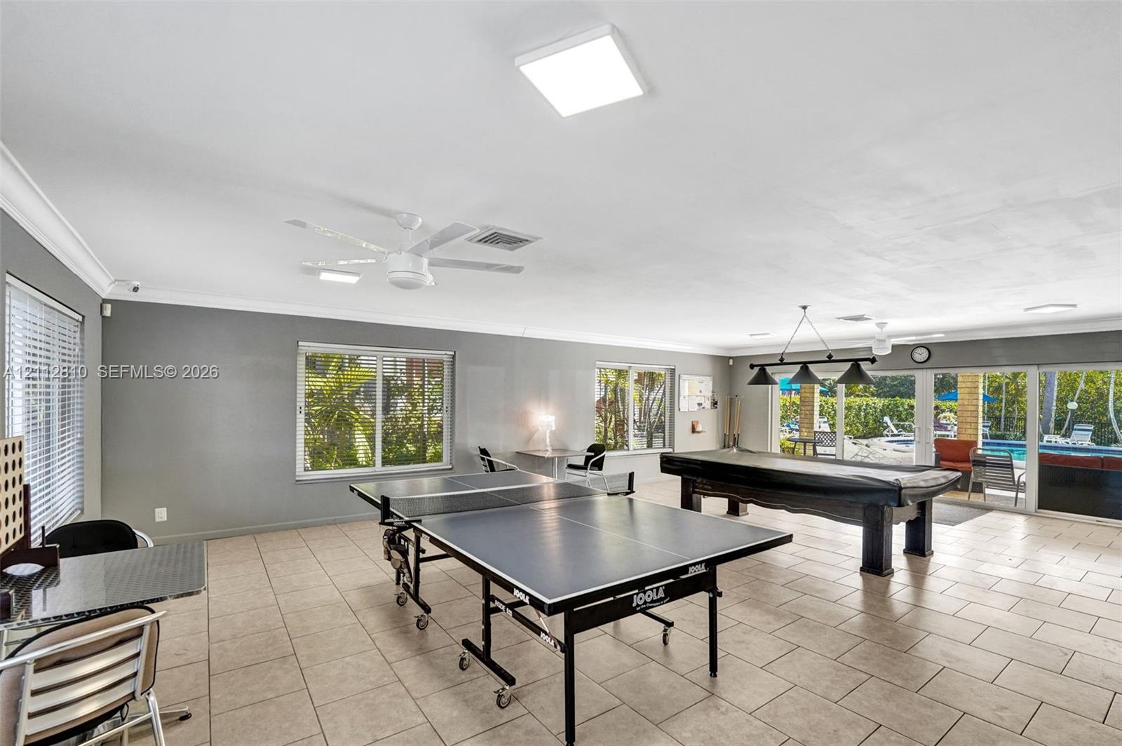 Spacious interior featuring neutral tile flooring, recessed and pendant lighting, ceiling fans, and large windows and glass sliding doors
