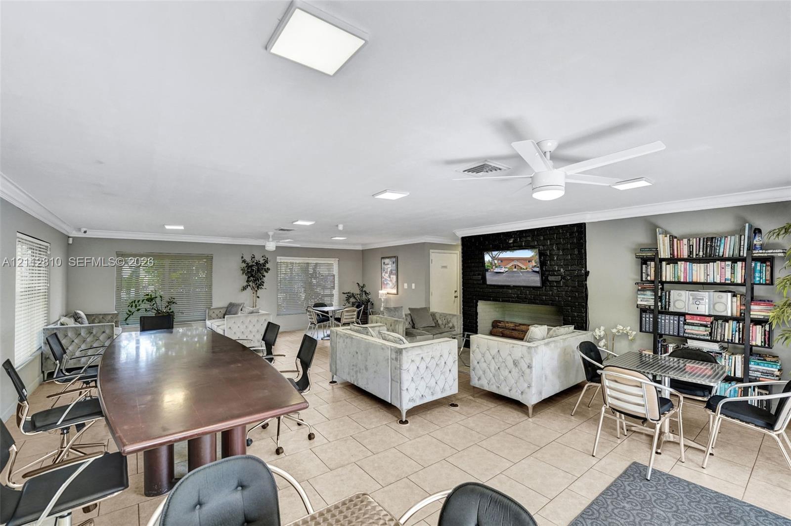 Open-concept area featuring oversized ceramic tile flooring, a dark masonry fireplace, built-in shelving, recessed lighting, and white ceiling-mounted fans