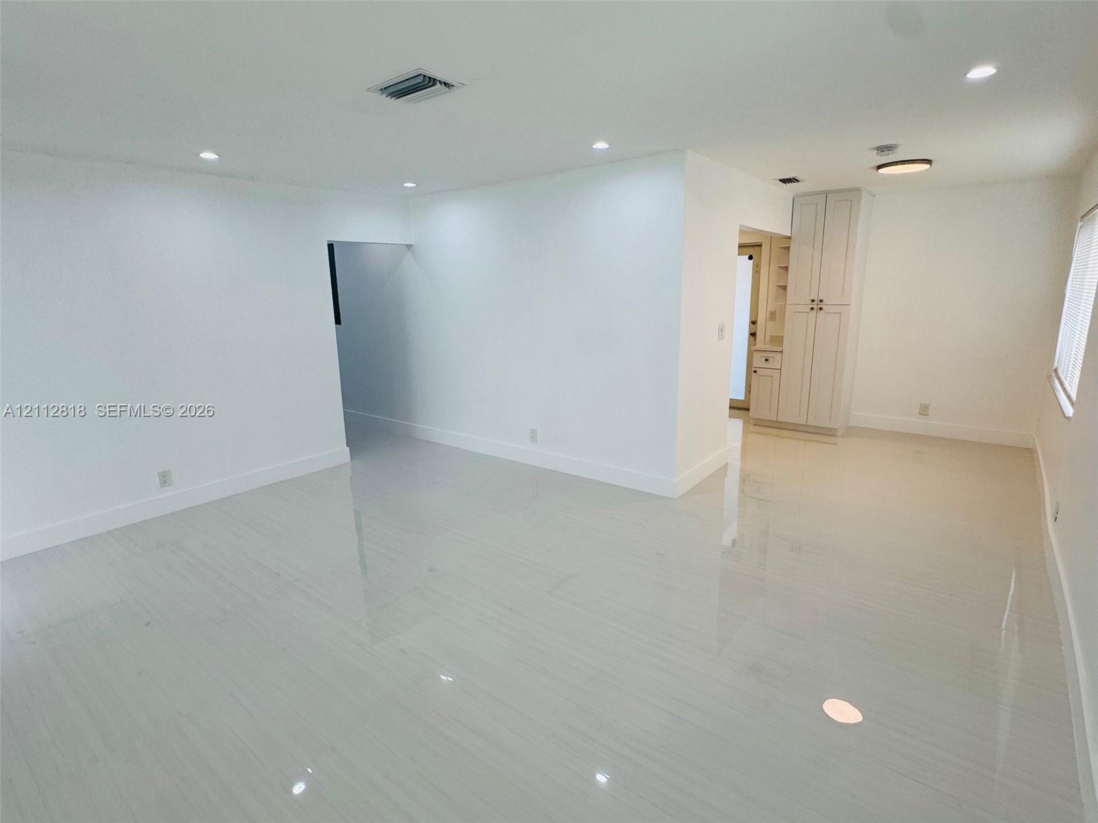 Neutral-toned interior featuring large-format tile flooring, recessed lighting, and built-in floor-to-ceiling cabinetry Neutral-toned interior featuring large-format tile flooring, recessed lighting, and built-in floor-to-ceiling cabinetry