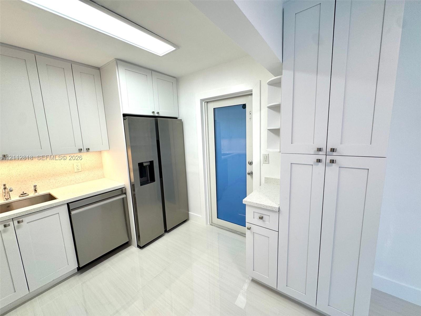 White shaker-style cabinetry, stainless steel appliances, solid-surface countertops, tile flooring, and integrated flush-mount ceiling lighting White shaker-style cabinetry, stainless steel appliances, solid-surface countertops, tile flooring, and integrated flush-mount ceiling lighting