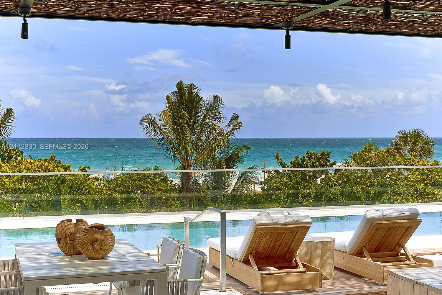 Outdoor terrace featuring a swimming pool with a glass railing and direct ocean exposure